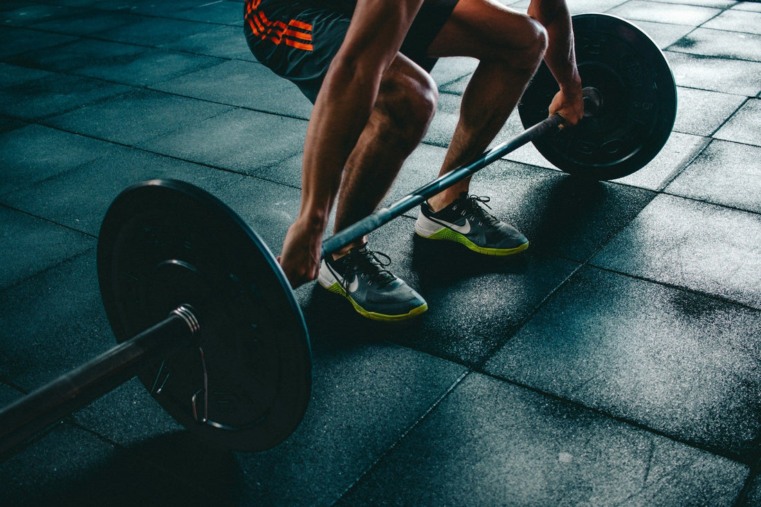 Sportler greift Langhantel im Gym – tiefe Bauchmuskeln stabilisieren den Rumpf beim Heben